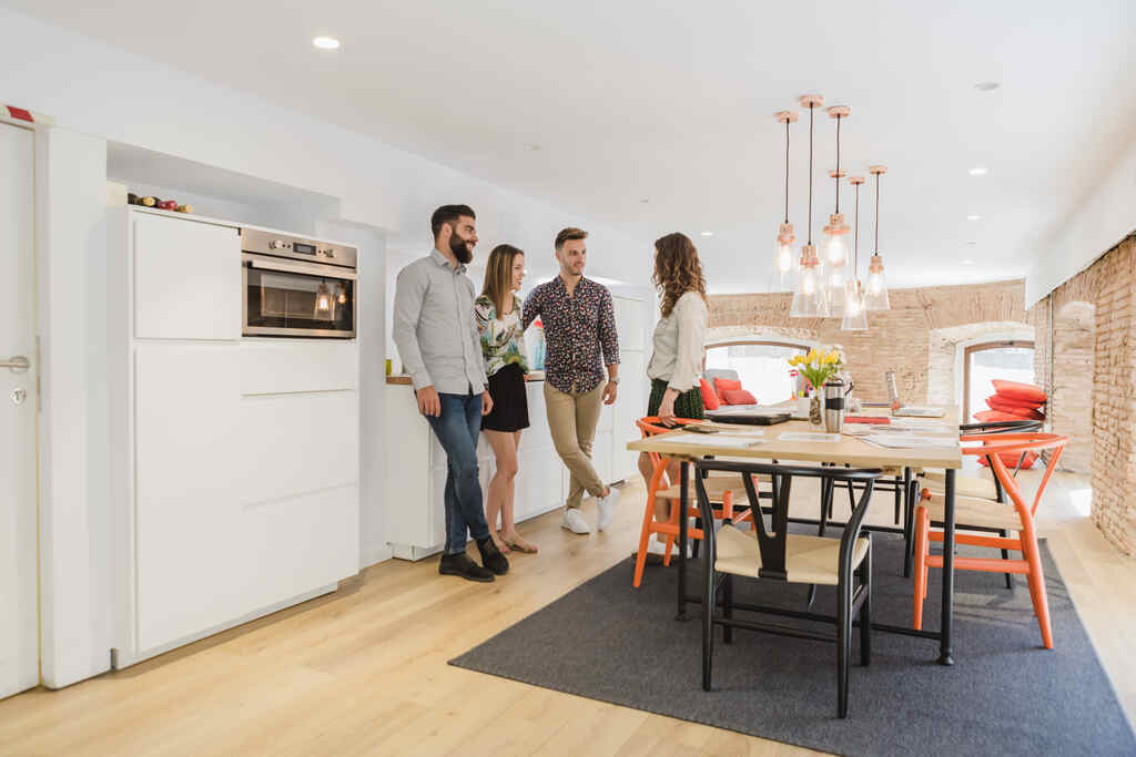 amigos reunidos conversando em pé na sala de jantar de um apartamento